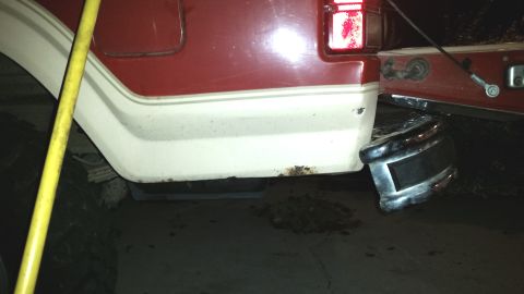 1985 Ford Bronco - The rear of a vehicle shows rust damage and a loose bumper, indicating repair needs.