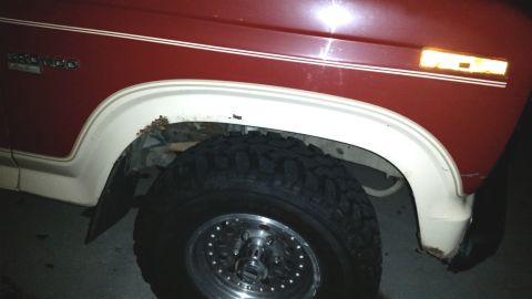 1985 Ford Bronco - Close-up of a 1985 Ford Bronco's side fender and wheel, highlighting areas of rust.