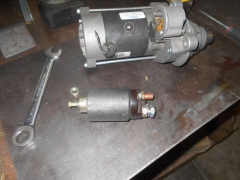 1992 Ford Bronco - A starter motor and its solenoid are laid out on a metal surface next to a wrench.