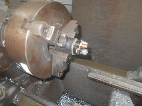 1992 Ford Bronco - A close-up view of a starter motor part being worked on in a lathe, with metal shavings scattered around.