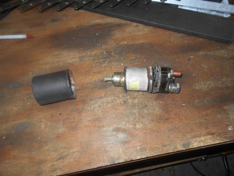 1992 Ford Bronco - Starter solenoid and protective cap resting on a workbench.