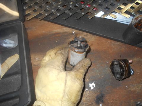 1992 Ford Bronco - Close-up of a starter solenoid part being held, with another component nearby on a workbench.