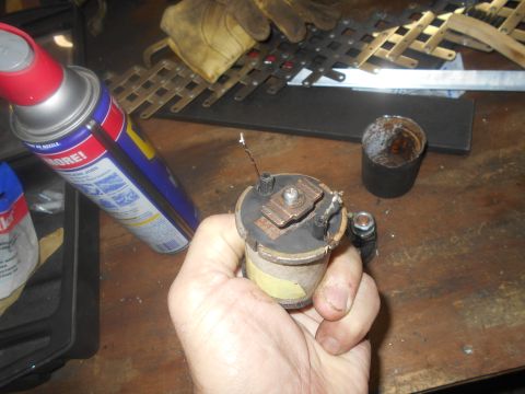 1992 Ford Bronco - A close-up of an ignition coil being held, with various tools and a can of lubricant visible in the background.