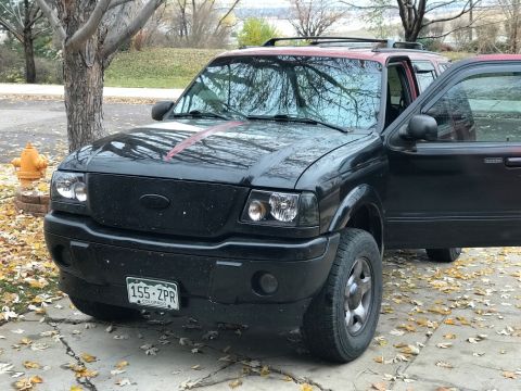 2000 Ford Explorer - A black Ford Ranger is parked outside with its driver's door ajar.