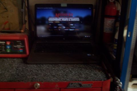 1995 Ford Bronco - Laptop displays a website for equipment, parts, and service, next to a battery charger and fire extinguisher.