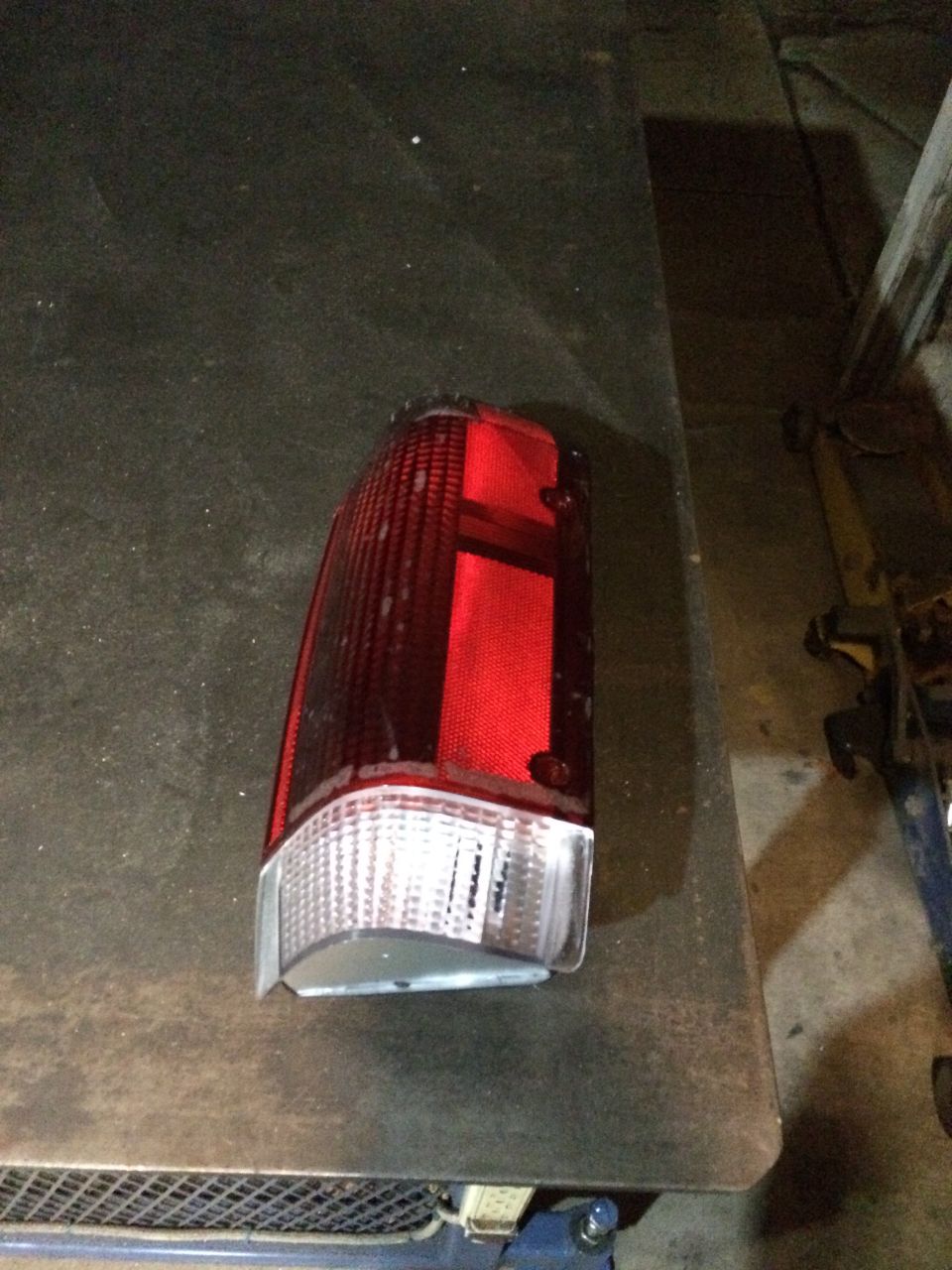 Red and clear plastic tail light assembly resting on a dark surface