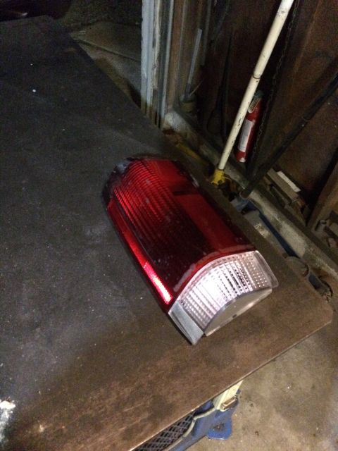 1989 Ford Bronco - A detached vehicle taillight rests on a workbench in a garage.
