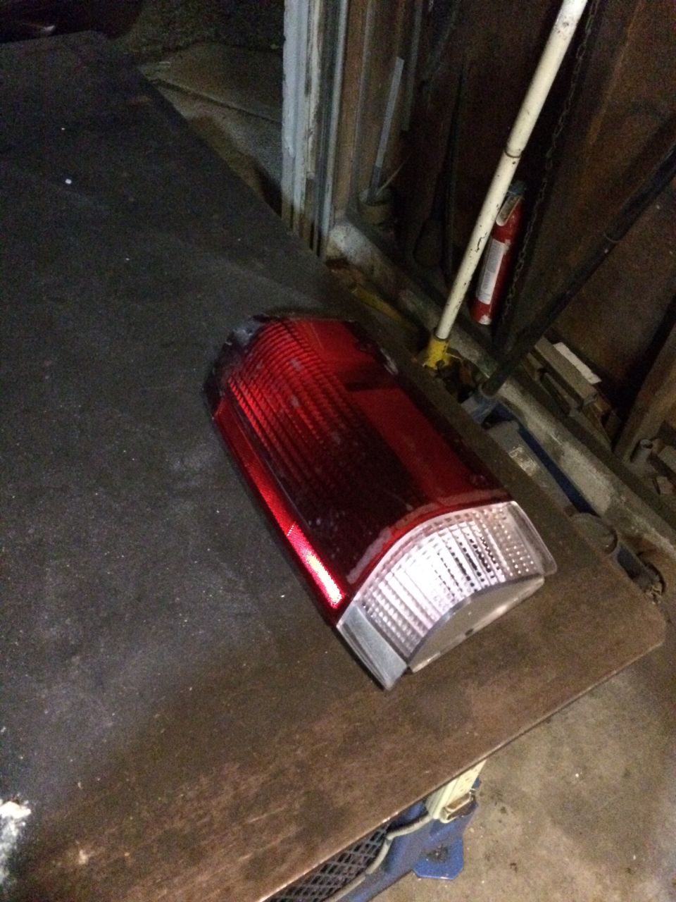 Red and clear plastic vehicle taillight on a dark surface