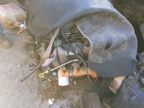 1989 Ford Bronco - An engine sits on the ground, partially covered, with a red gas can nearby.