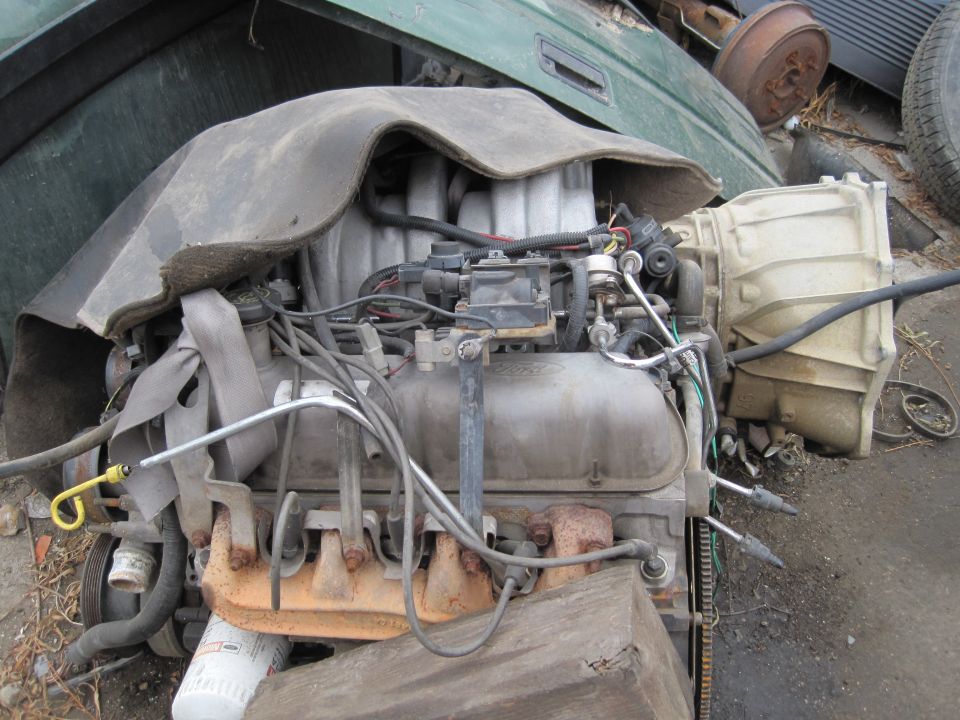 Ford V8 engine with transmission attached, covered by insulation. Looks like it's from a 1989 vehicle