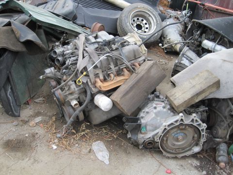 1989 Ford Bronco - Scrap yard scene with engine, transmission, and tire. No complete vehicle visible.
