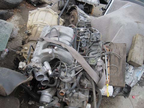 1989 Ford Bronco - Engine and transmission assembly, likely from a Ford vehicle, is shown in a junkyard setting.