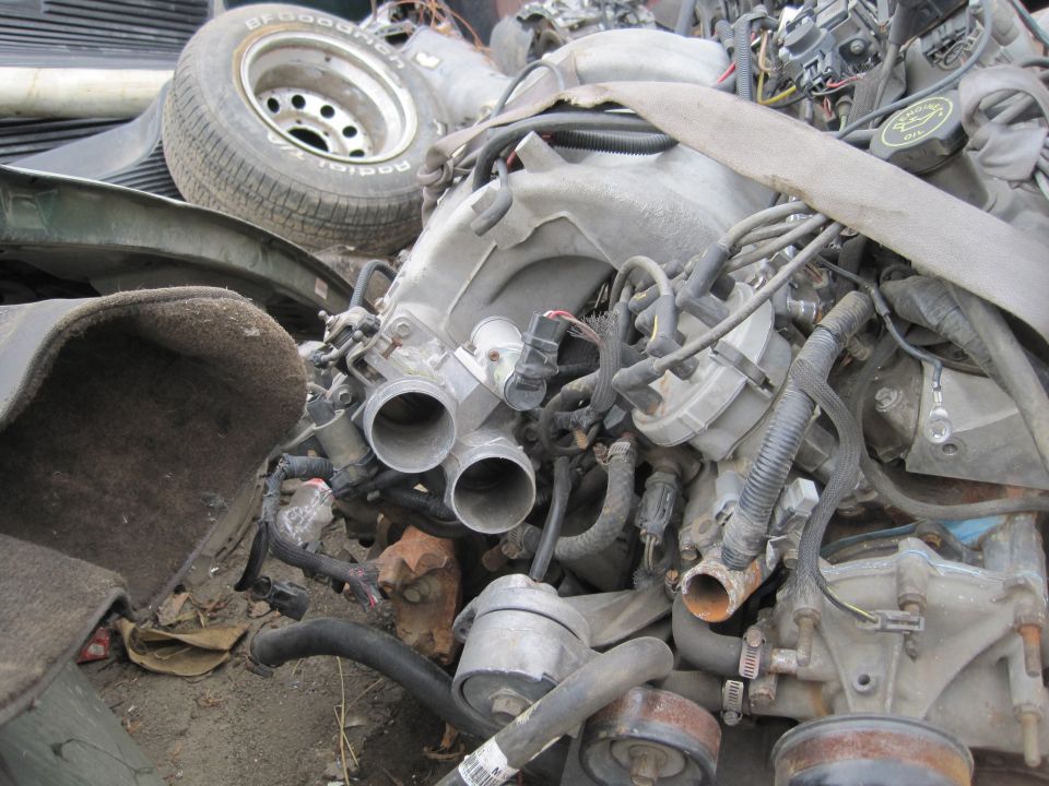 Engine components and a BFGoodrich tire in a pile of parts