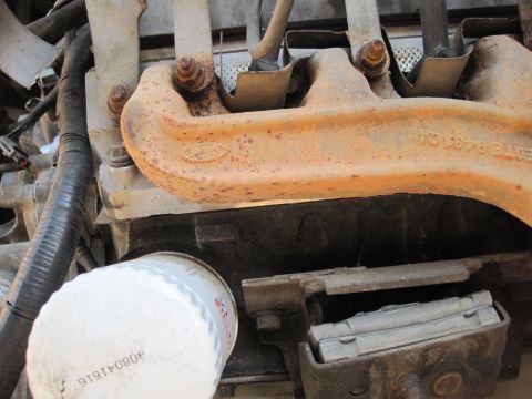 1989 Ford Bronco - A close-up view of a rusty Ford exhaust manifold, showing the Ford logo and some part numbers.