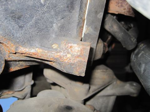 1989 Ford Bronco - Close-up of rusted metal bracket and suspension components, likely from a vehicle's undercarriage.