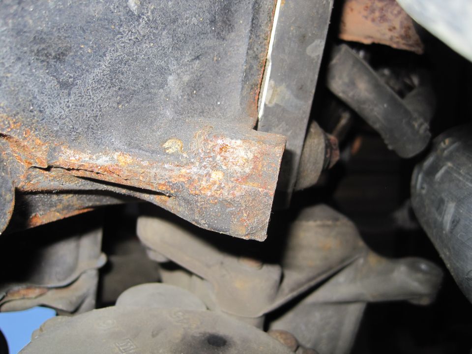 Close-up of rusted metal bracket with suspension parts visible underneath
