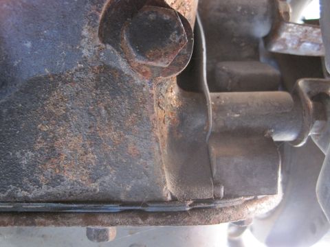 1989 Ford Bronco - Close-up of a rusty engine block casting with visible bolts and metal components.