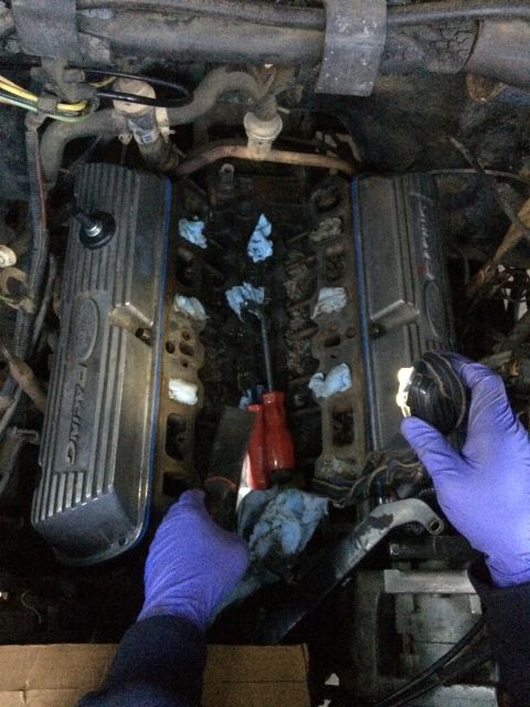 1989 Ford Bronco - Engine valve covers and intake manifold during reassembly, with tools and rags present.
