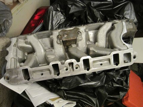 1989 Ford Bronco - Engine intake manifold part, likely for a V8 engine, shown on a workbench.