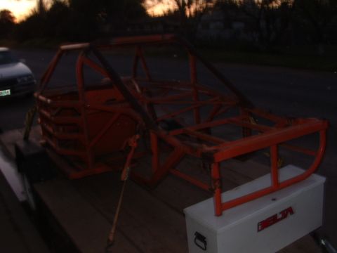 1990 Ford Bronco - Orange roll cage frame on a trailer, with a toolbox and a car in the background.