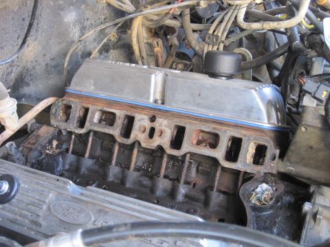 1989 Ford Bronco - Close-up view of a disassembled engine, focusing on the valve cover and manifold area.