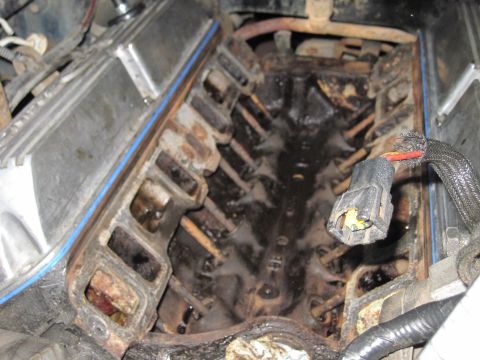 1989 Ford Bronco - Close-up of a dirty engine intake manifold, showing internal components and a blue gasket.