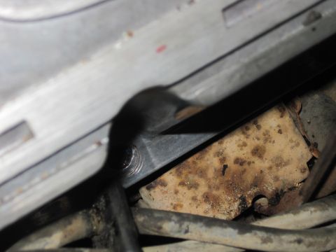 1989 Ford Bronco - Close-up of a rusted metal bracket and hoses, likely part of an engine assembly.