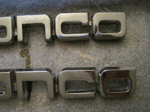1989 Ford Bronco - Close-up of two chrome Bronco emblems, showing wear and tear.