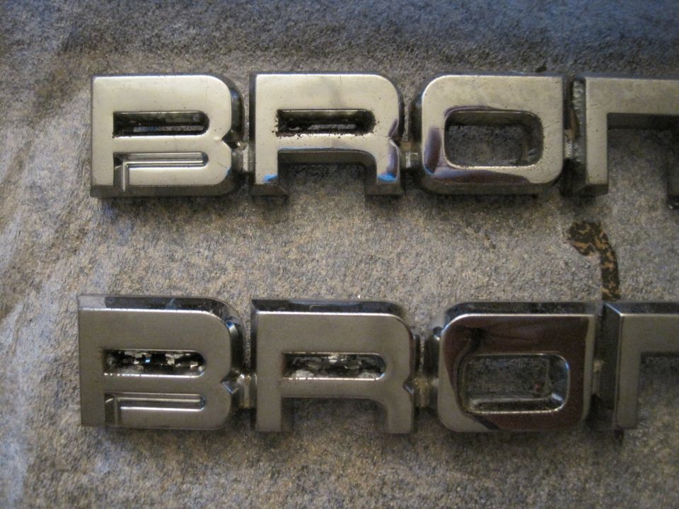 Two chrome Bronco emblems on a textured surface