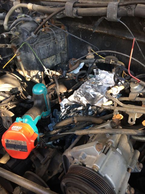 1989 Ford Bronco - Close-up view of a cluttered engine bay, with tools and aluminum foil obscuring some components.