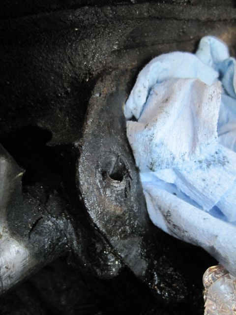 1989 Ford Bronco - A close-up view of a dirty engine part, with a blue shop towel partially obscuring the view.