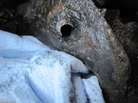1989 Ford Bronco - A close-up view of a greasy engine component, partially covered by a blue cloth, likely during reassembly or maintenance.