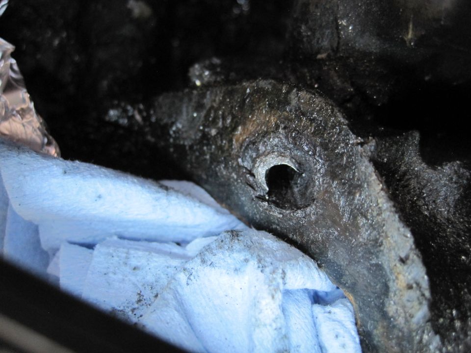 Close-up of a greasy engine component with blue shop towels underneath