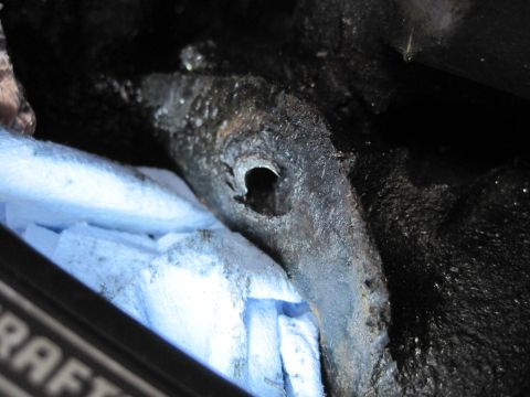 1989 Ford Bronco - Greasy engine component with a hole, placed on blue shop towels during reassembly.