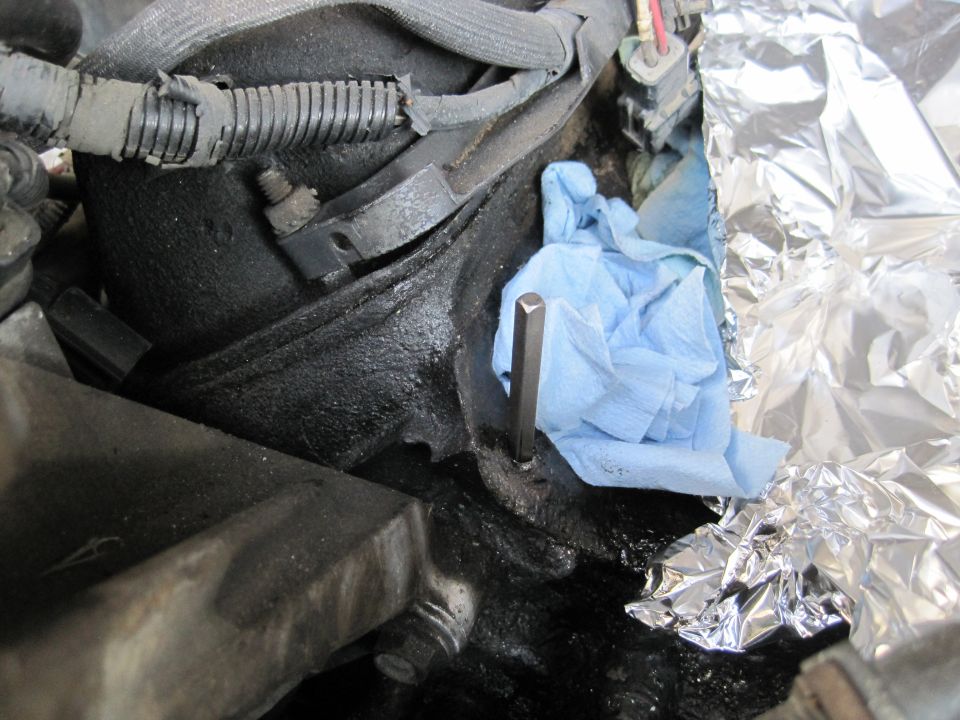 Hex wrench in engine part with blue shop towel and foil