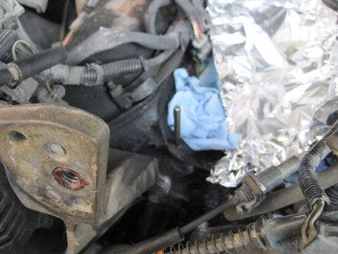 1989 Ford Bronco - Engine bay components with a blue glove and foil wrap visible during reassembly.