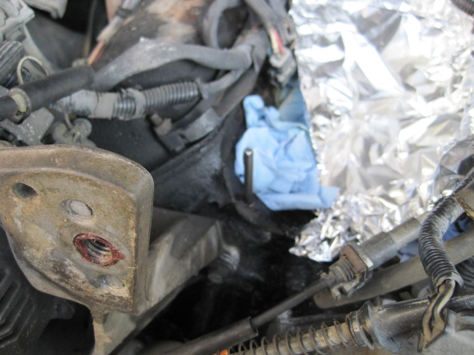 Close-up of engine bay showing wiring, a blue glove, and aluminum foil covering part of the engine