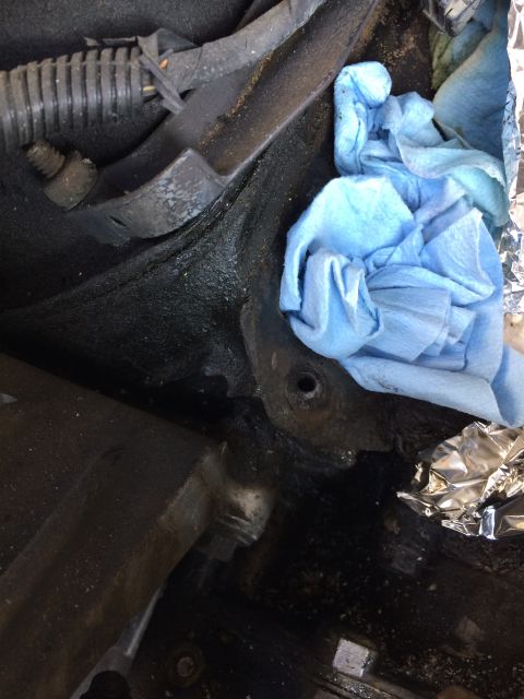 1989 Ford Bronco - Engine bay components are visible, covered in grease, with blue shop towels and foil nearby.