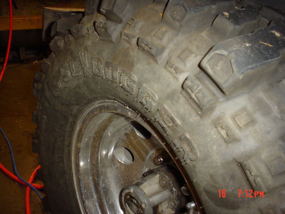 Close-up of a large off-road tire with 'BELLBOGGER' molded into the sidewall, mounted on a chrome wheel