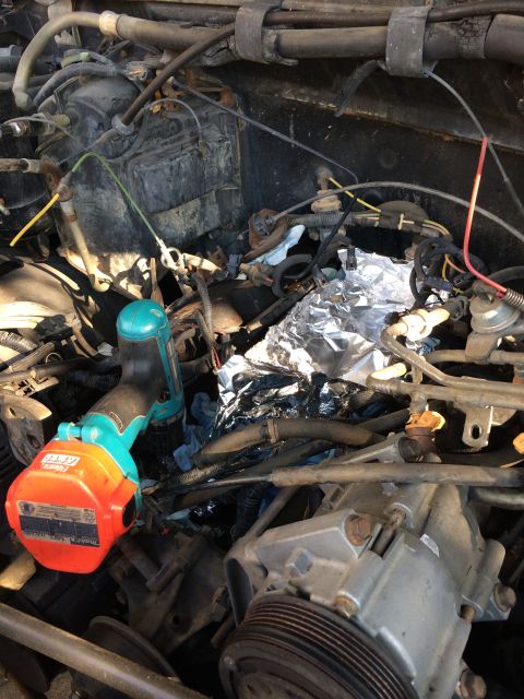 1989 Ford Bronco - Close-up view of a cluttered engine bay with various components and tools.