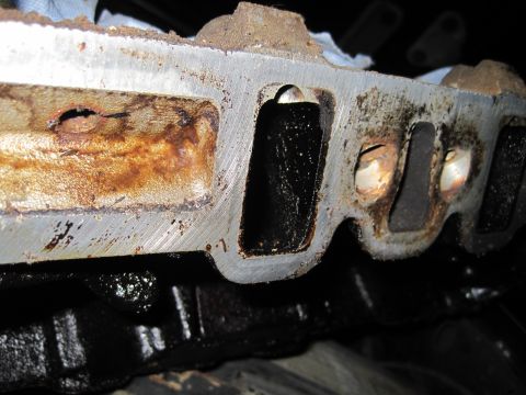 1989 Ford Bronco - Close-up view of a heavily used engine intake manifold, showing signs of rust and oil accumulation.