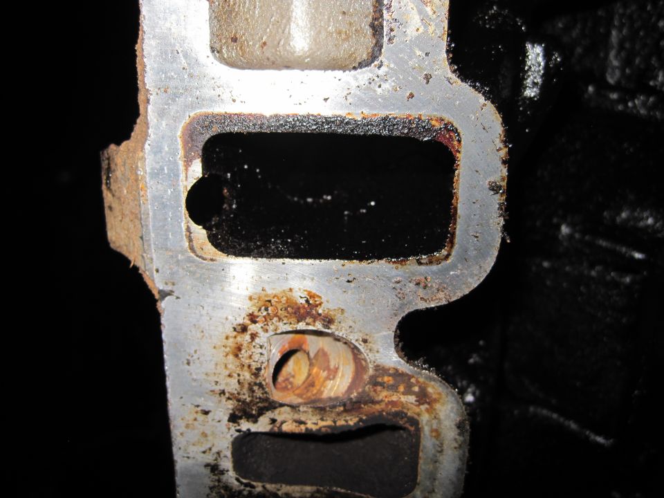Close-up of a dirty, rusty intake manifold port with black residue inside