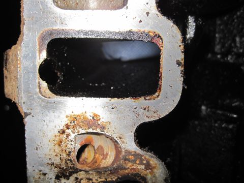 1989 Ford Bronco - A close-up view of a heavily corroded engine intake manifold part shows significant wear and residue.