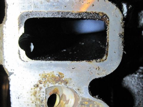 1989 Ford Bronco - Close-up view of an engine intake manifold port showing significant carbon deposits and wear.