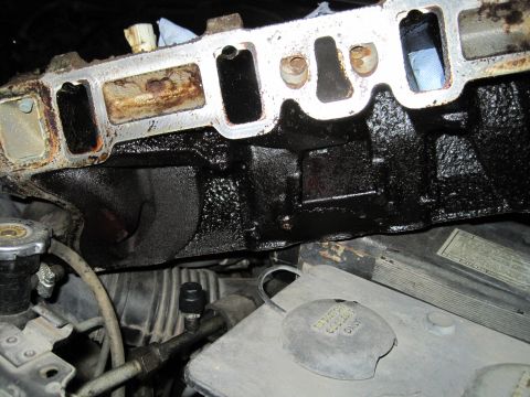 1989 Ford Bronco - Close-up of a greasy engine intake manifold with visible rust and debris.