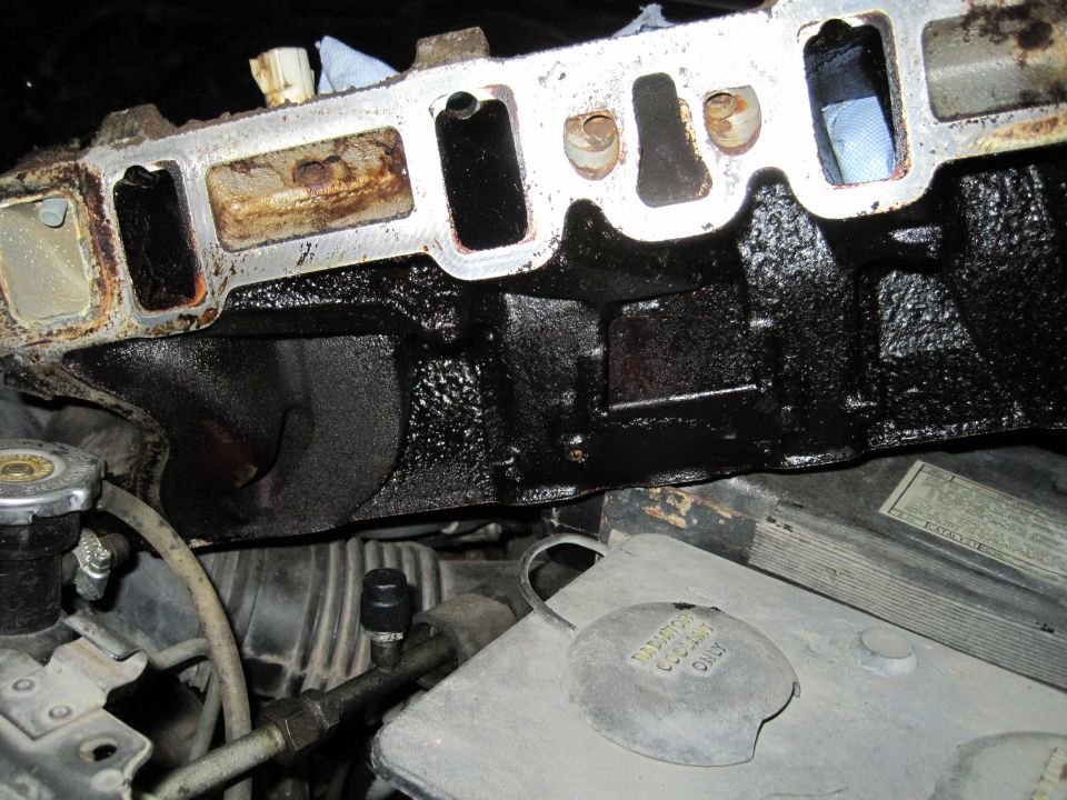 Dirty engine intake manifold above radiator cap and coolant reservoir