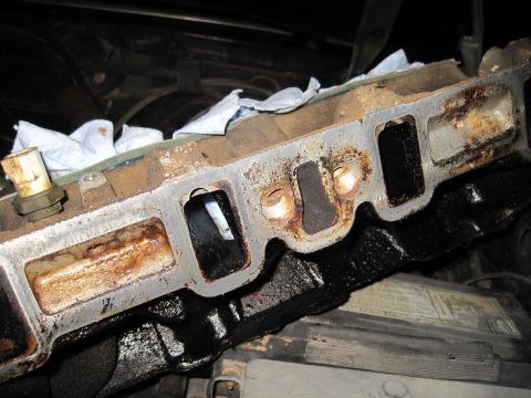 1989 Ford Bronco - Engine intake manifold showing signs of rust and wear, with white cloth inserted into ports.