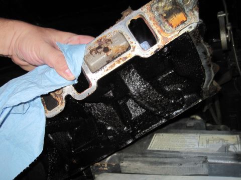 1989 Ford Bronco - A hand cleans an engine intake manifold, revealing its internal structure.