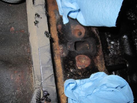 1989 Ford Bronco - This image shows a close-up of a rusted metal bracket, likely from a vehicle's interior, with blue towels placed over parts of it.