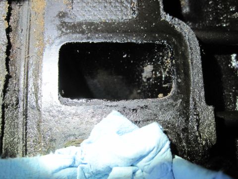 1989 Ford Bronco - A close-up view of a dirty engine component, possibly an intake manifold, with a blue cloth obscuring part of the frame.